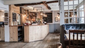 En hyggelig bar med træmøbler, en tavle med menukort og et rustikt loftsdesign.
