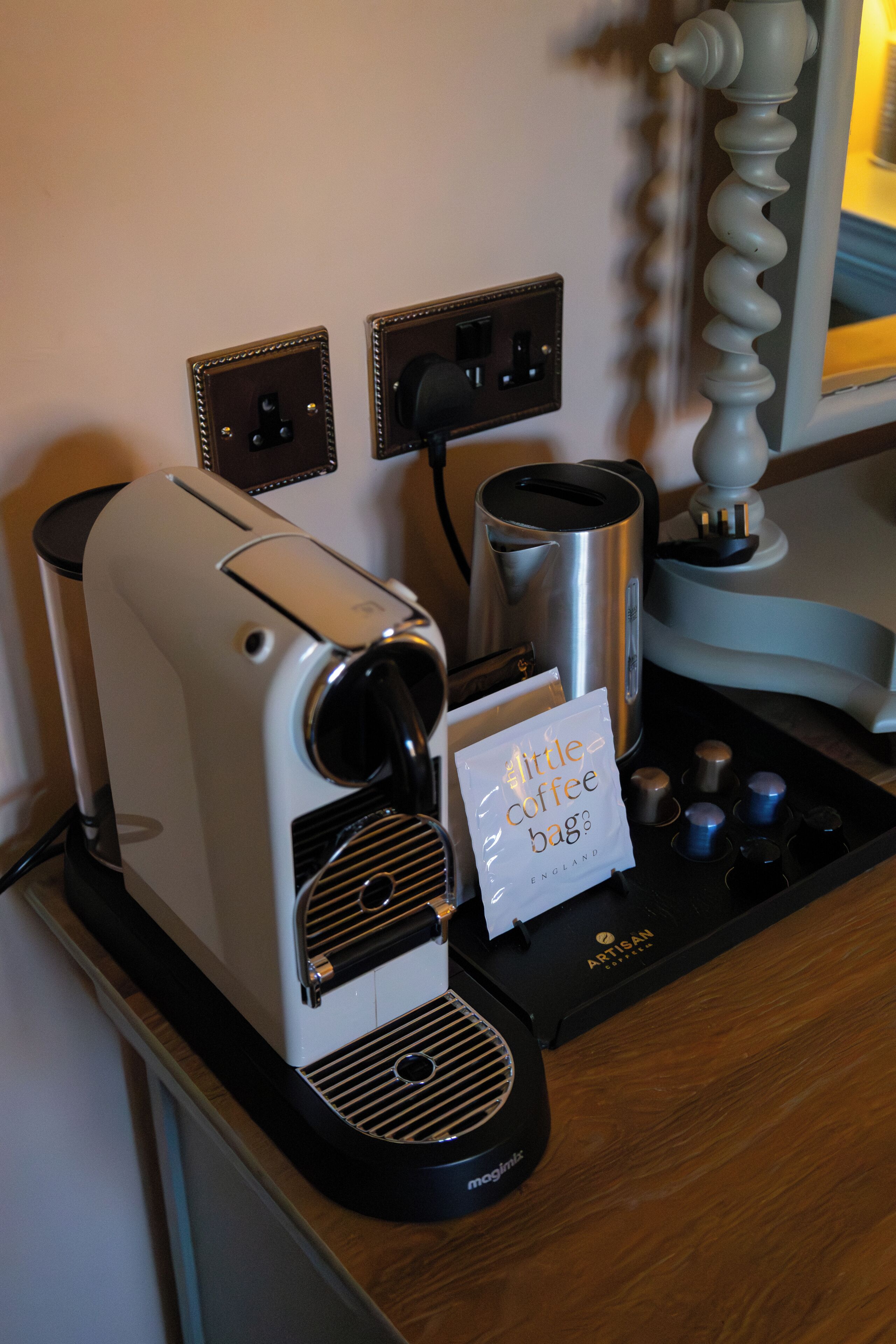 Eine Kaffeemaschine mit Aufkleber 'kleiner Kaffeebeutel', ein Wasserkocher und eine Kaffeemaschine auf einer Holzauskład.