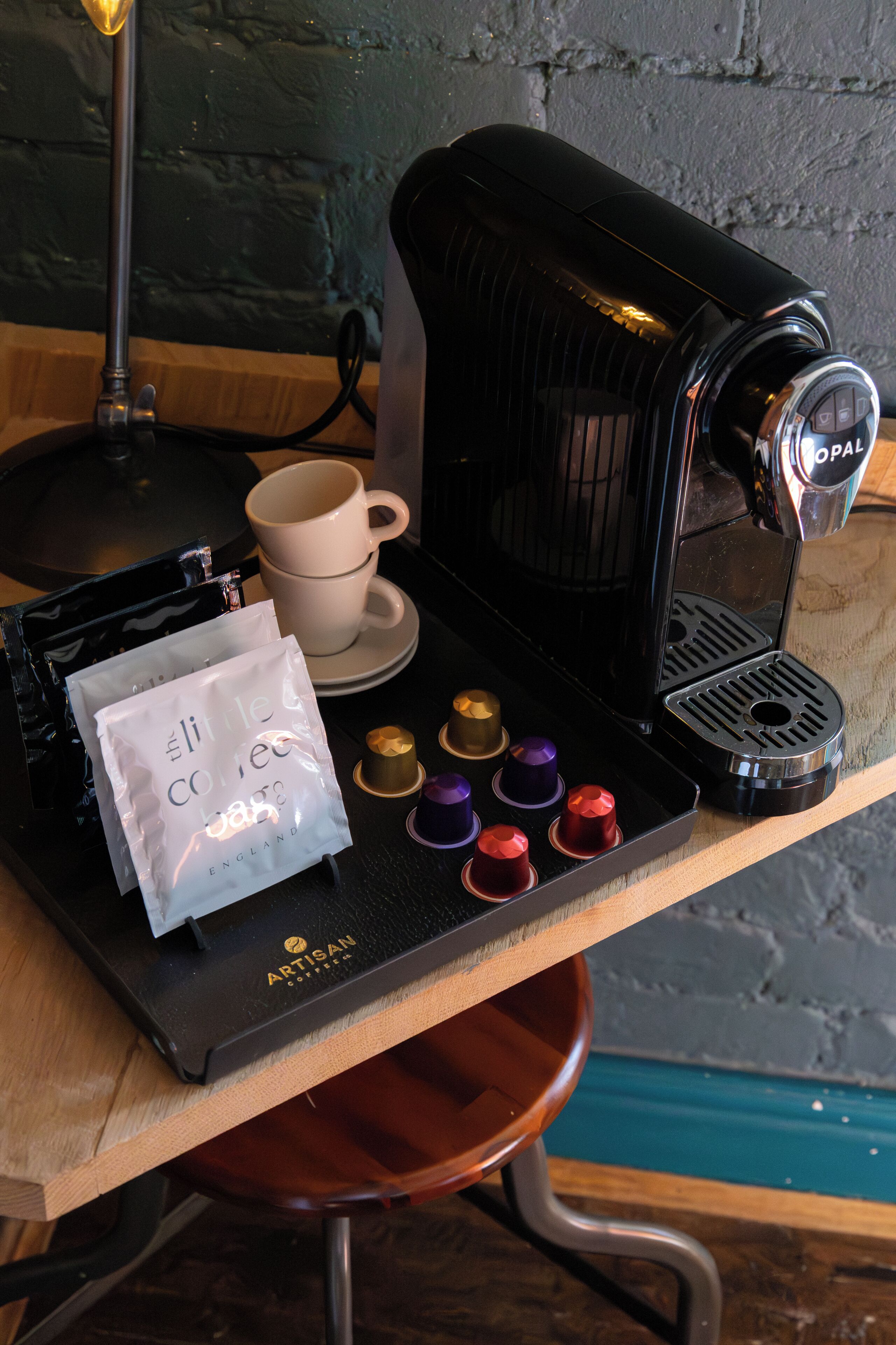 A coffee machine, a cup, and a bag of coffee on a wooden table.