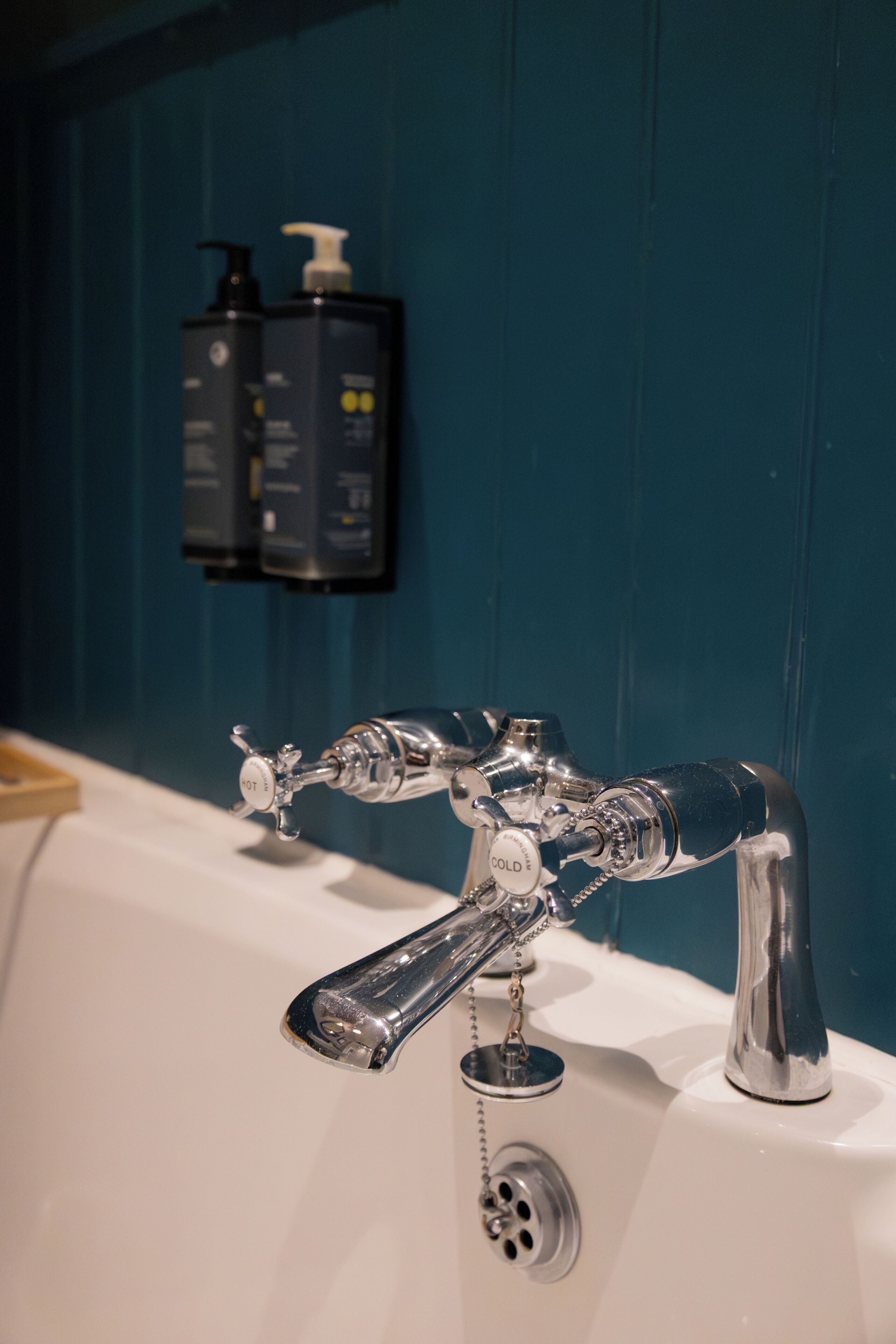 Un baño con grifo de cromo, lavamanos y pared azul.