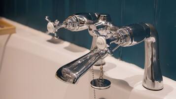 Un baño con grifo de cromo, lavamanos y pared azul.