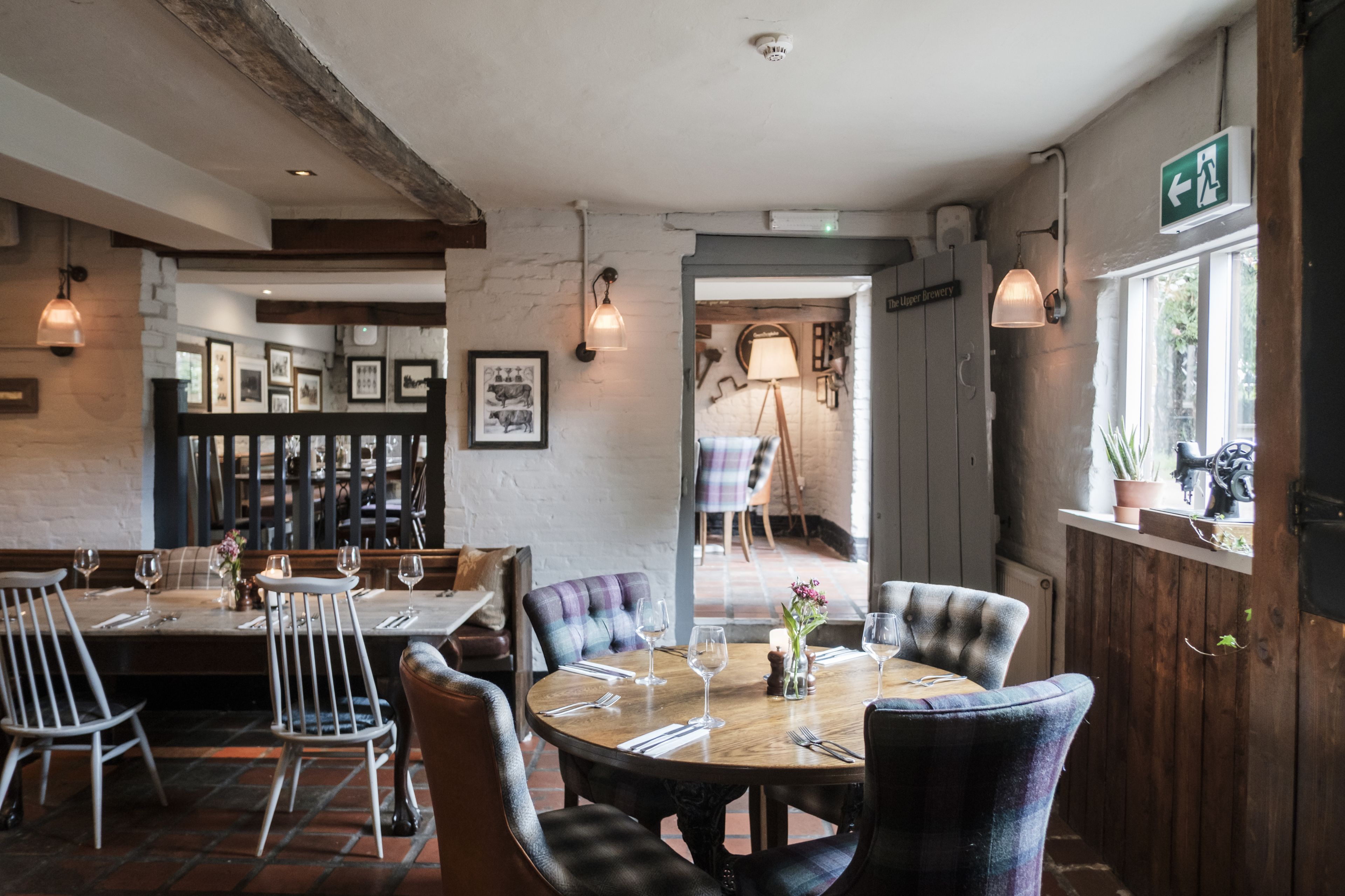 A restaurant interior with wooden tables, cushioned chairs, and framed pictures on the walls.