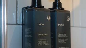 Two black bottles of Anyah hair care products mounted on a wall.