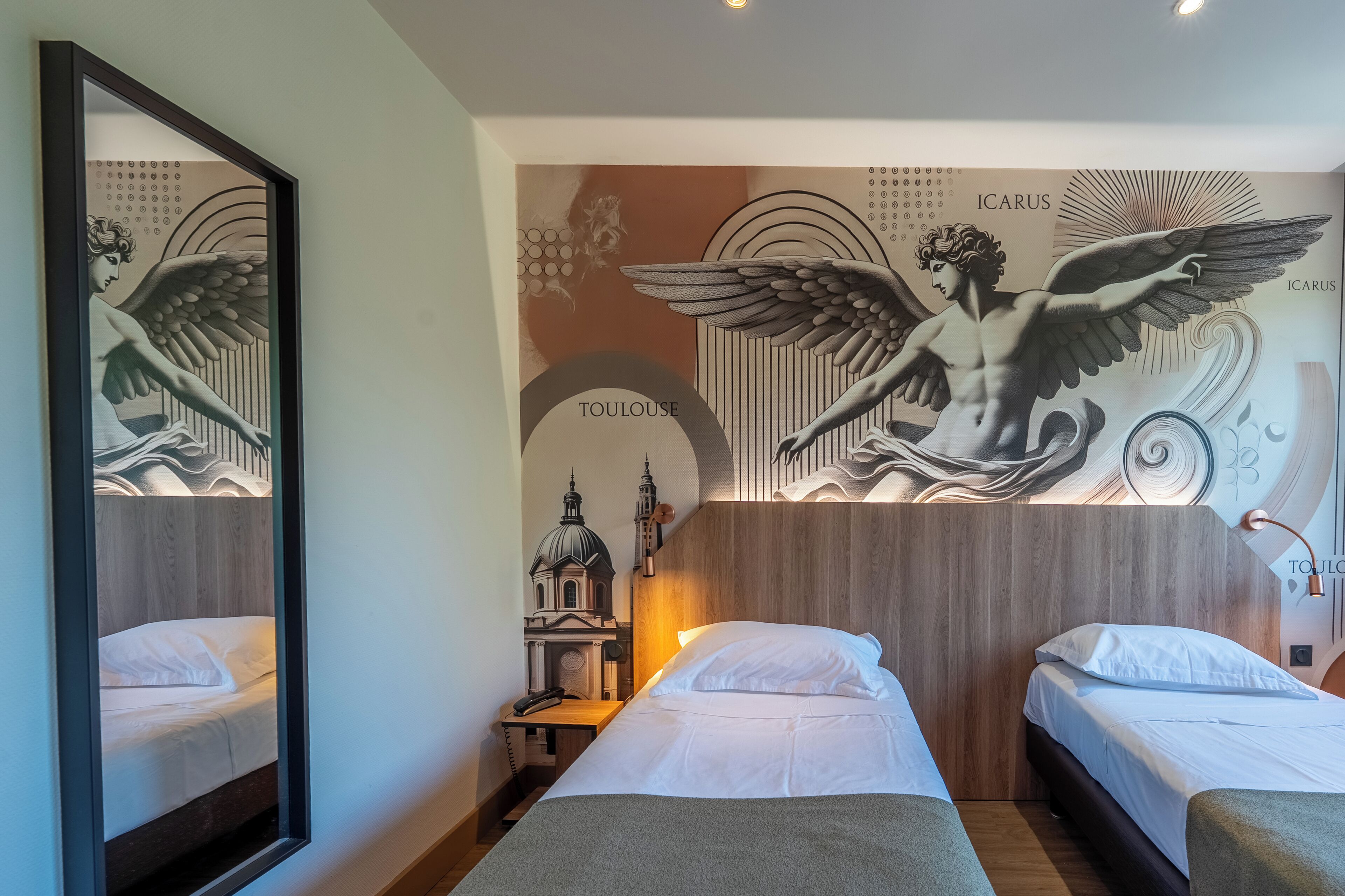 Une chambre d’hôtel avec deux lits simples, un grand miroir et une fresque murale représentant une figure angélique.