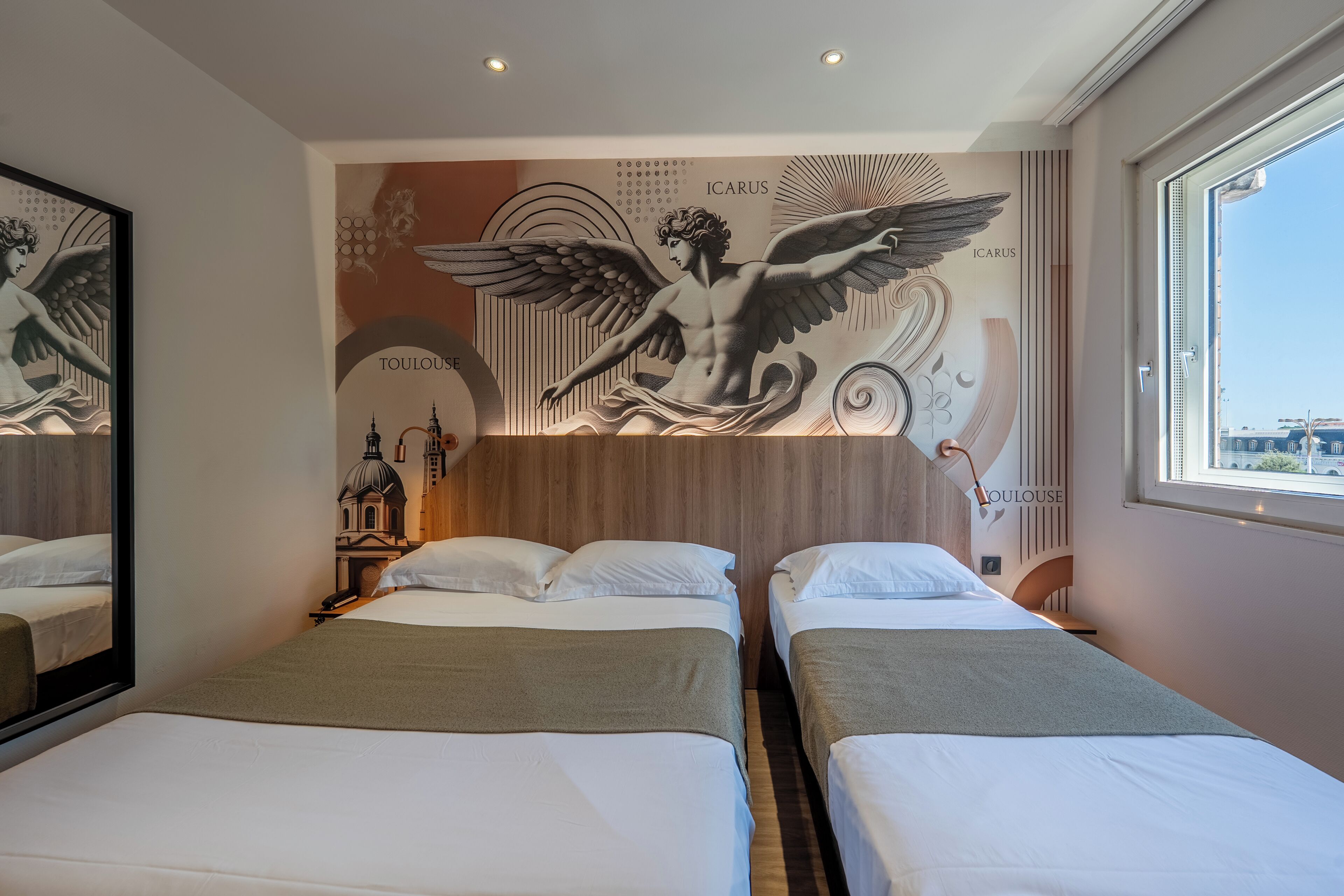 A hotel room with two beds, a wooden headboard, a mural with winged figures, and a view of the city.