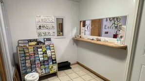 A hotel room with a bulletin board displaying travel guides, a small shelf with toiletries, and a bucket of paint. - Motel Oasis (Moses Lake)