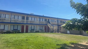 A two-story motel with a central staircase, a small front garden, and a clear blue sky. - Motel Oasis (Moses Lake)