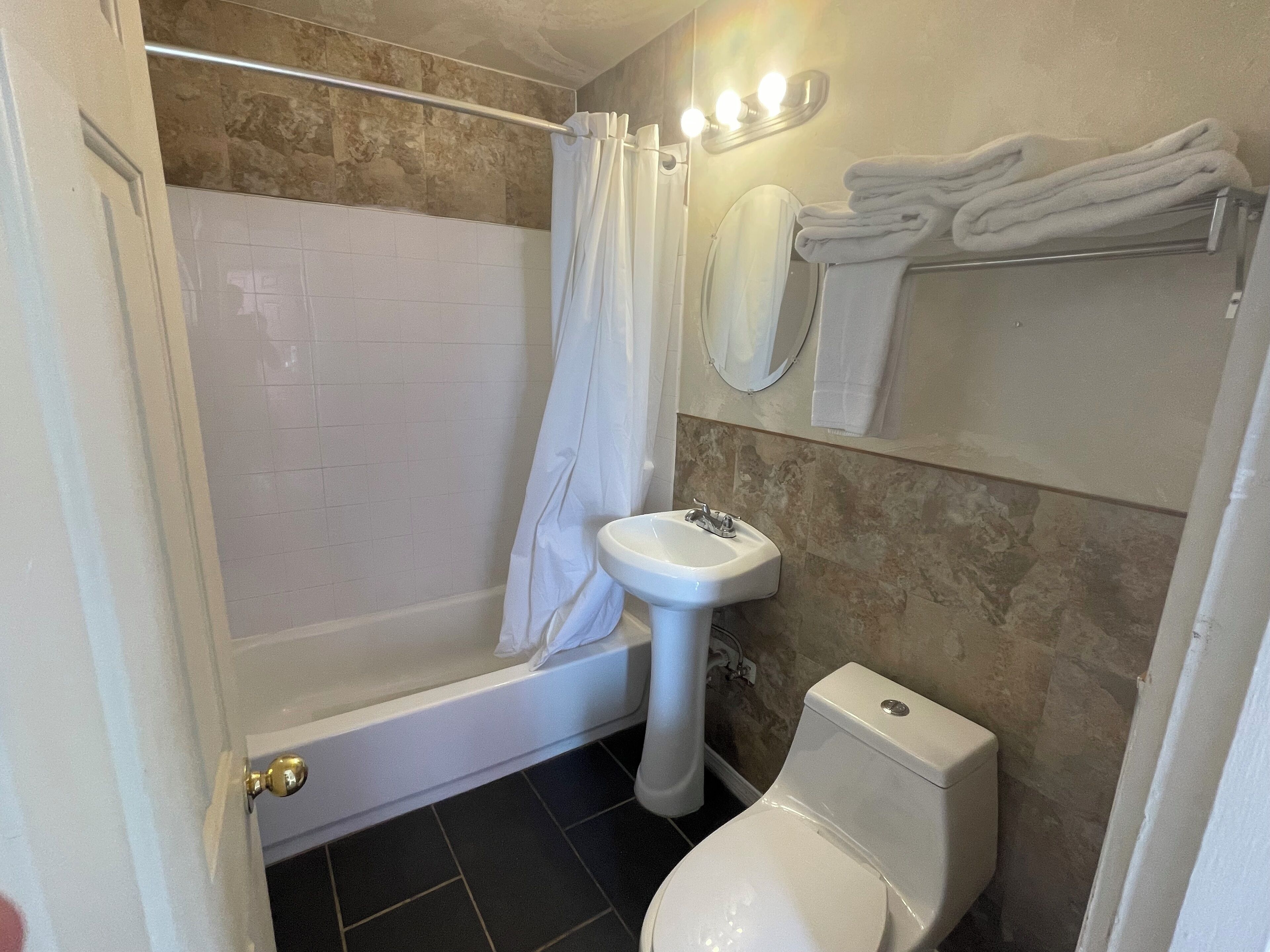 A bathroom with a shower, a sink, a toilet, and a towel rack.