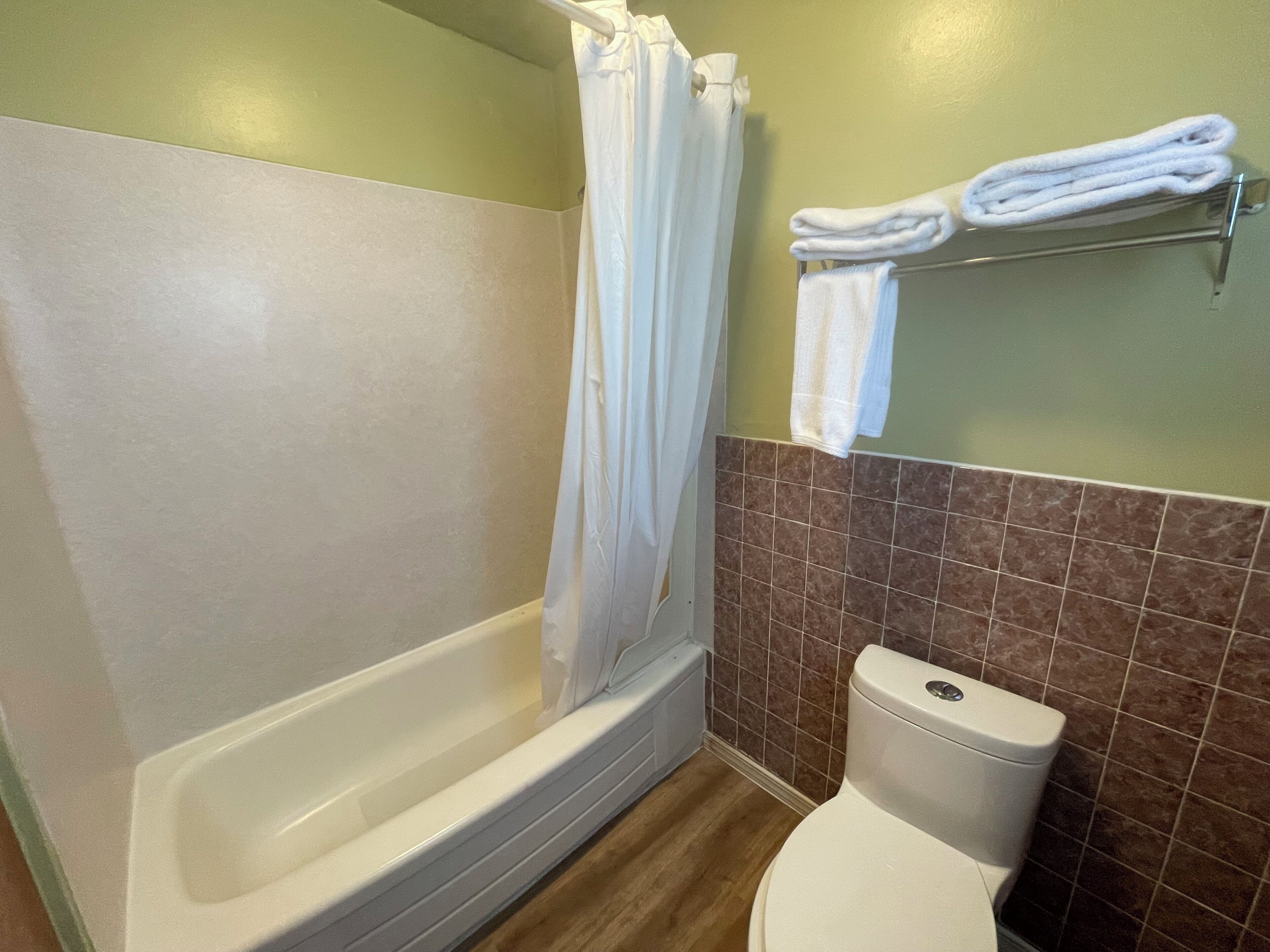 Un baño con bañera, inodoro y toallero.