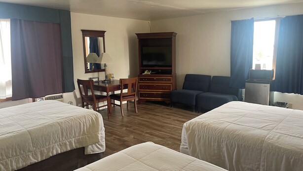 A hotel room with two beds, a desk with a chair, a television, and a dresser. - Motel Oasis (Moses Lake)