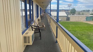 A motel with a covered corridor, air conditioning units, and outdoor seating. - Motel Oasis (Moses Lake)