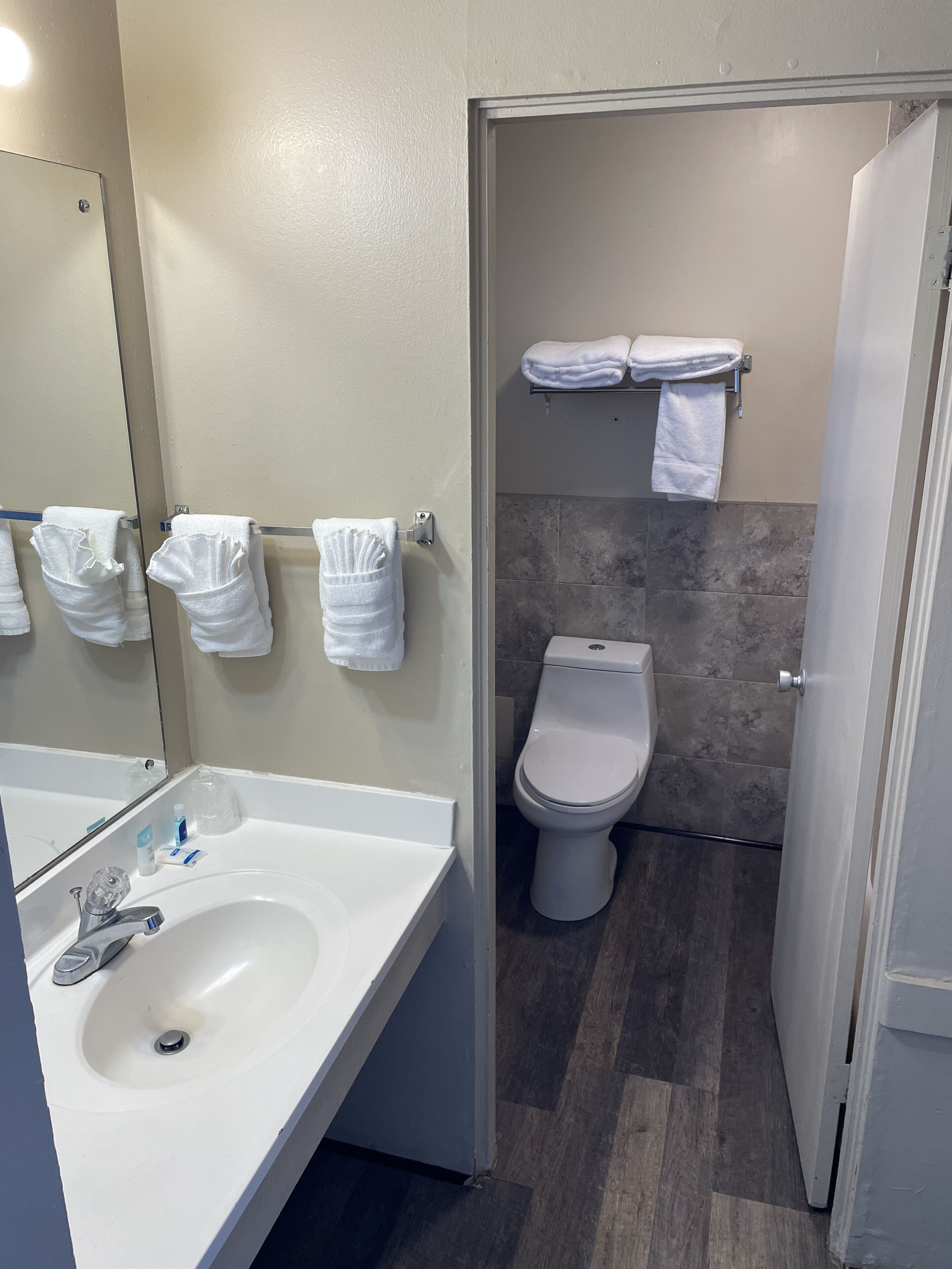 A bathroom with a sink, mirror, and two towels hanging on hooks.