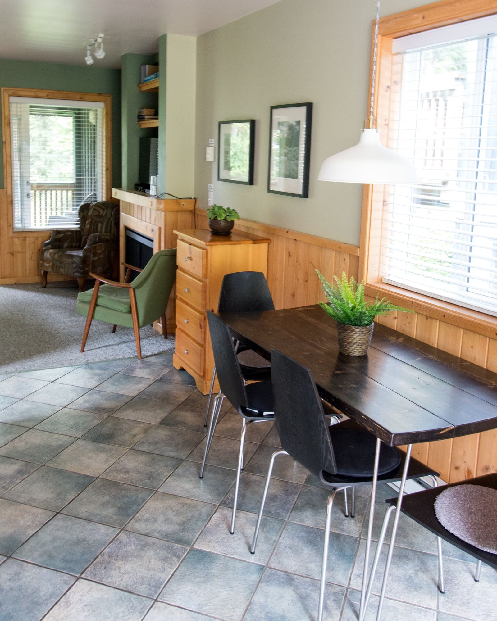 A dining area with a wooden table, black chairs, and a potted plant.