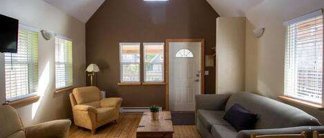 A living room with a sloped ceiling, a sofa, a chair, a coffee table, and a television.