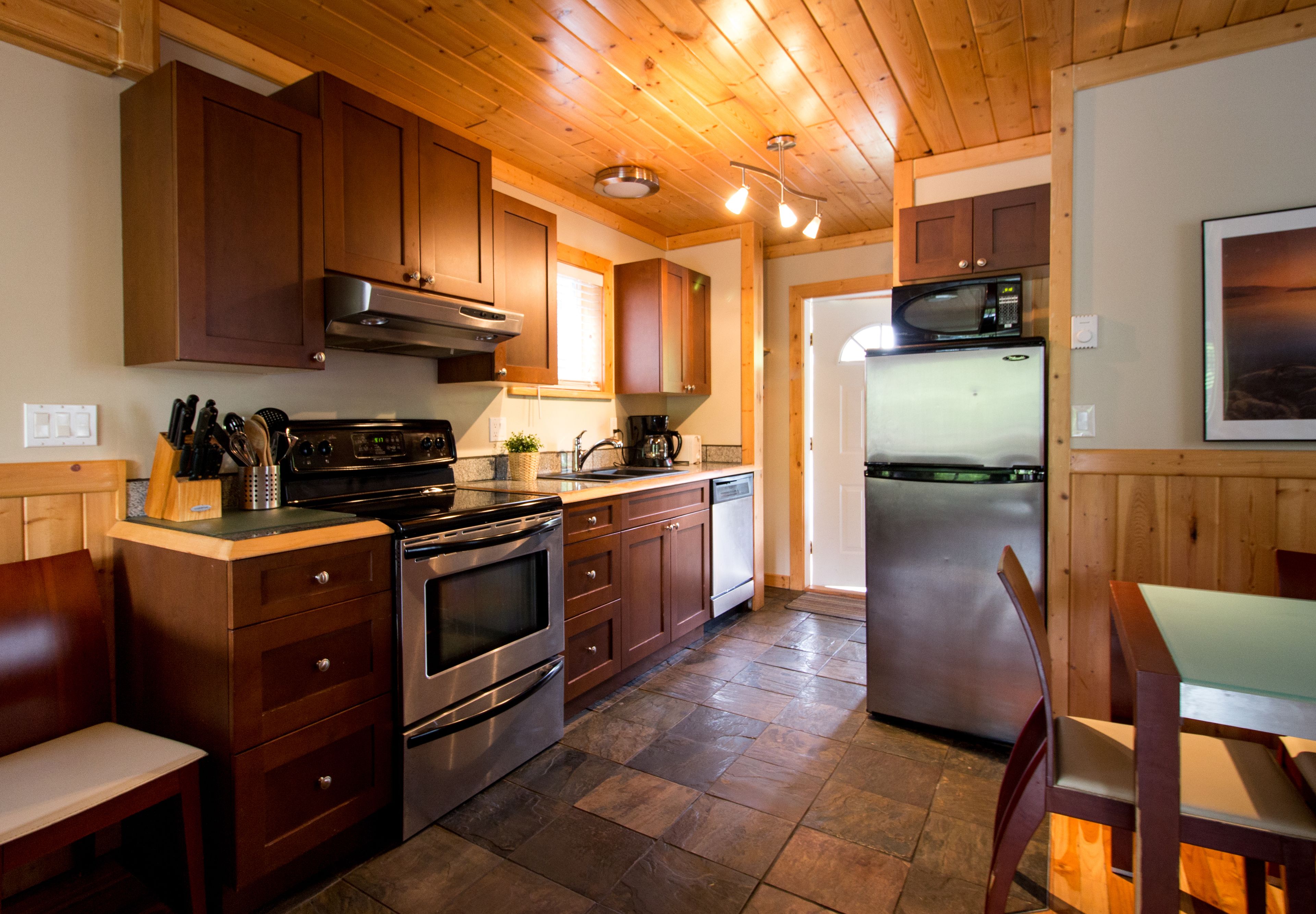 Una cocina con armarios de madera, estufa, microondas y refrigerador.