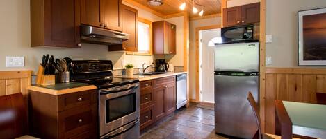 Una cocina con armarios de madera, estufa, microondas y refrigerador.