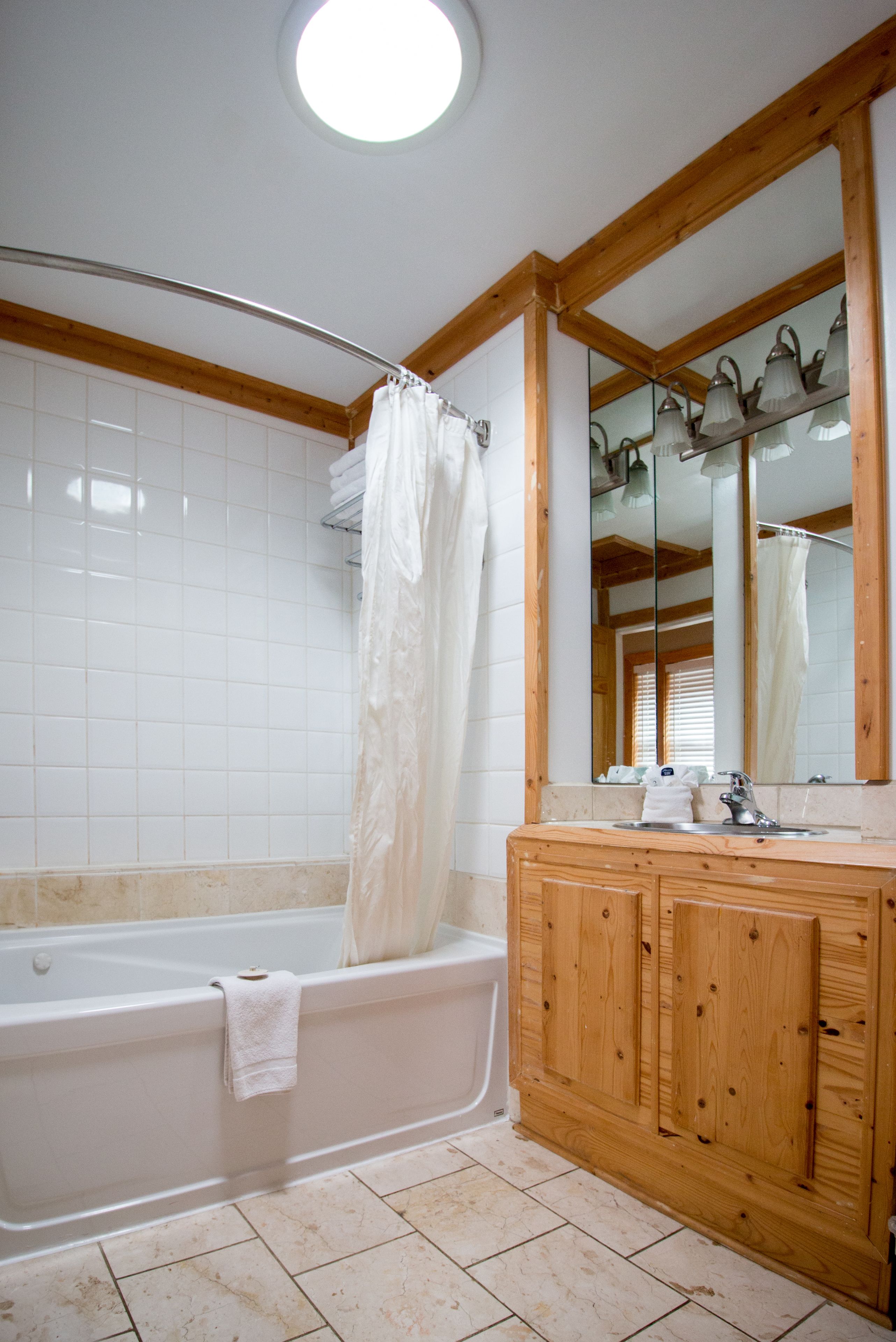 Ein Badezimmer mit Holzwaschtisch, einer weißen Badewanne und einem großen Spiegel.