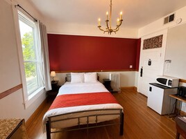 Habitación de hotel con cama, radiador, microondas, escritorio y ventana con cortinas.