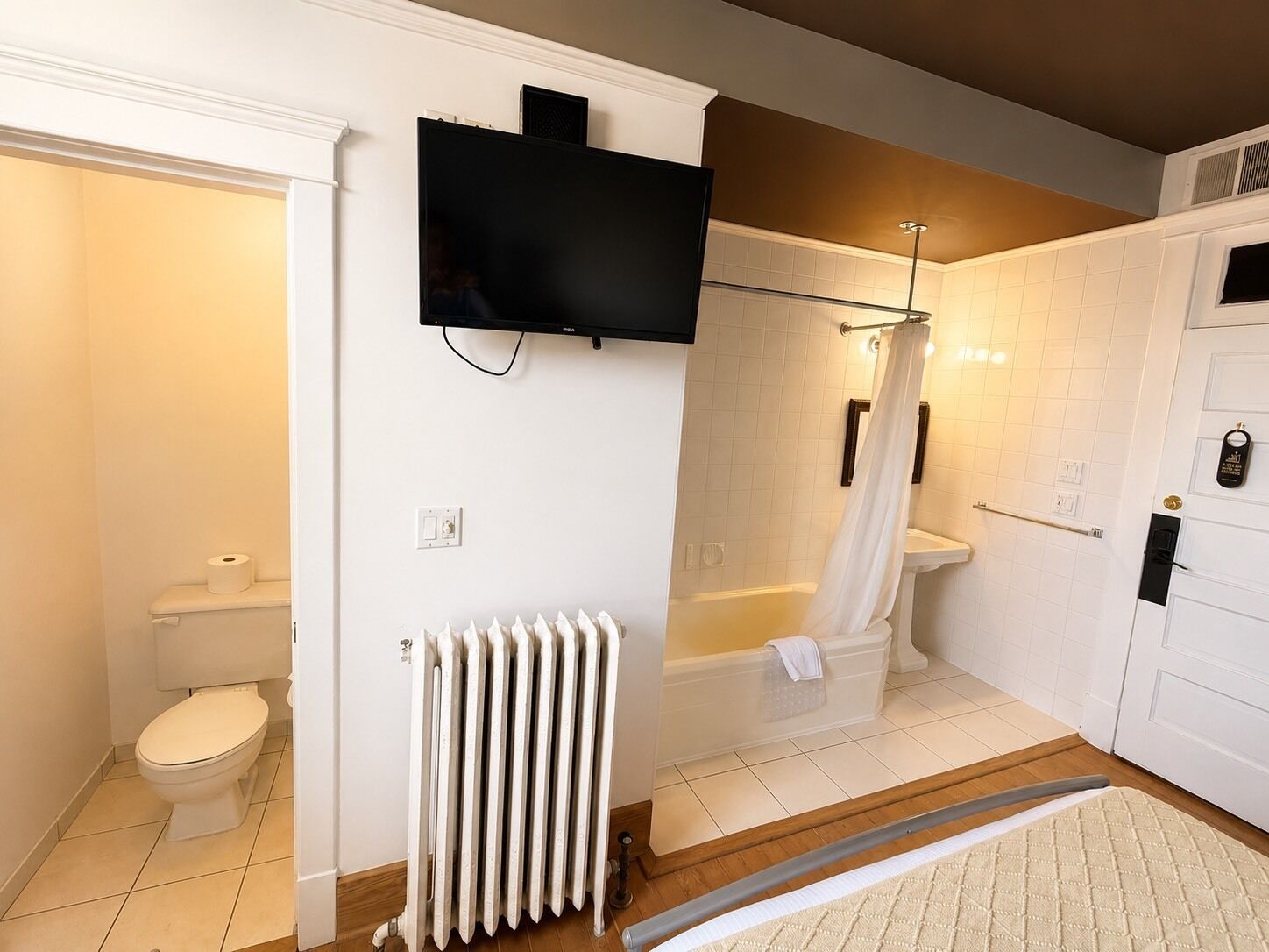 Une salle de bain comprenant des toilettes, un radiateur, une douche avec une porte en verre et une baignoire.