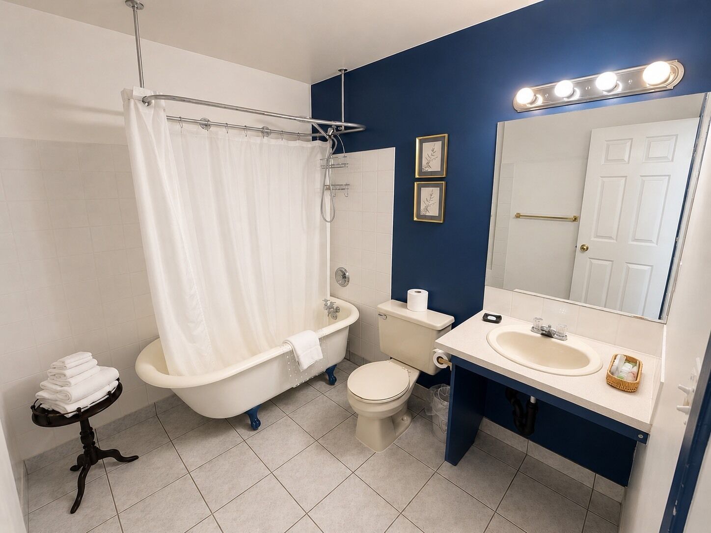 A bathroom with a bathtub, toilet, sink, and a mirror with lights.