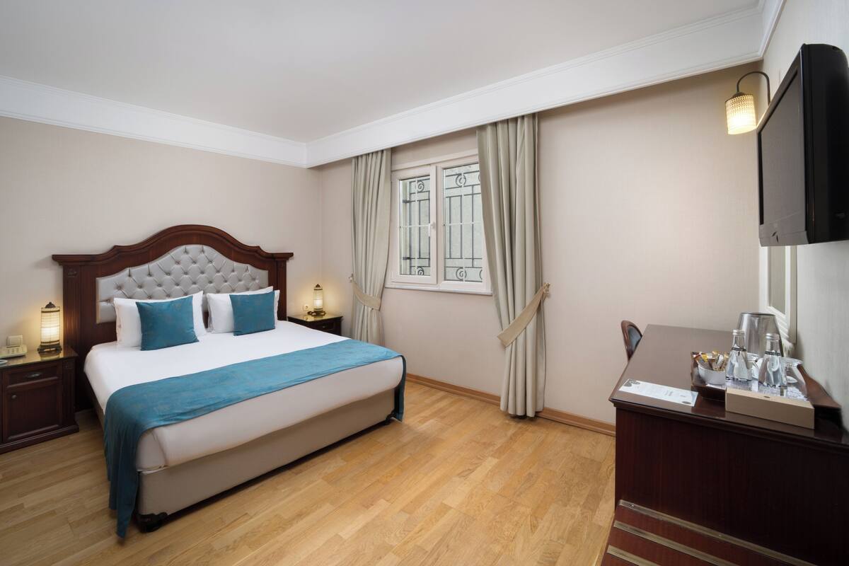 Une chambre d’hôtel avec un grand lit, une tête de lit en bois et un téléviseur à écran plat fixé au mur.