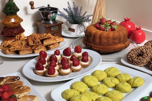 Una selezione di dolci, tra cui pasticcini, biscotti e una torta bundt, disposti su un tavolo.