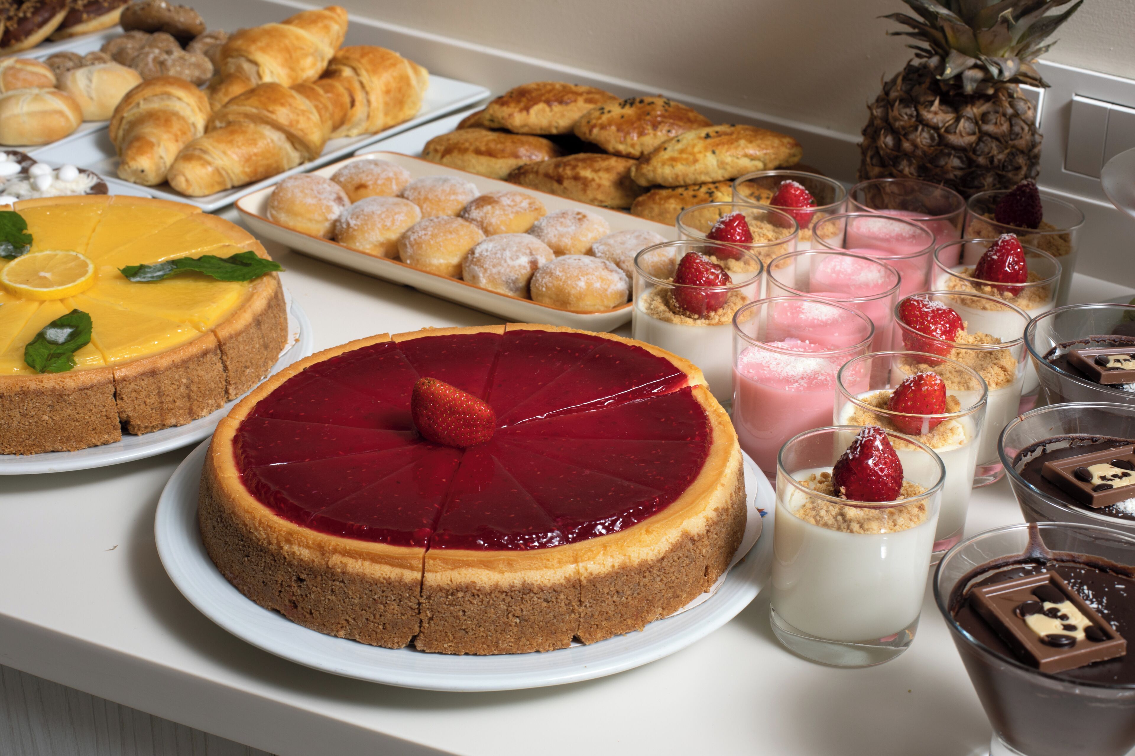 A variety of desserts including cakes, pastries, and fruit-based desserts on a buffet table.