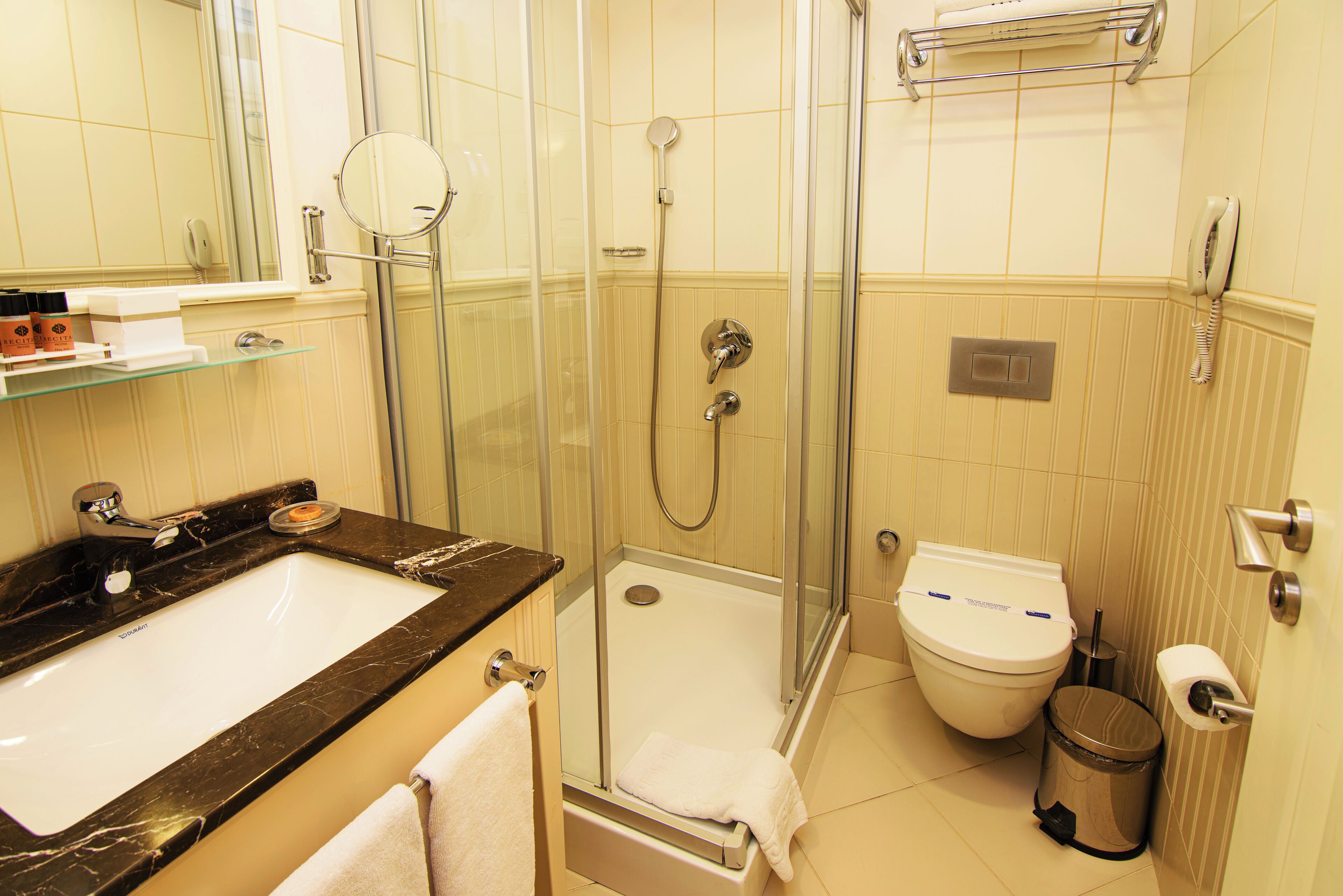 Un baño con ducha envuelta en vidrio, un lavabo blanco y un inodoro.