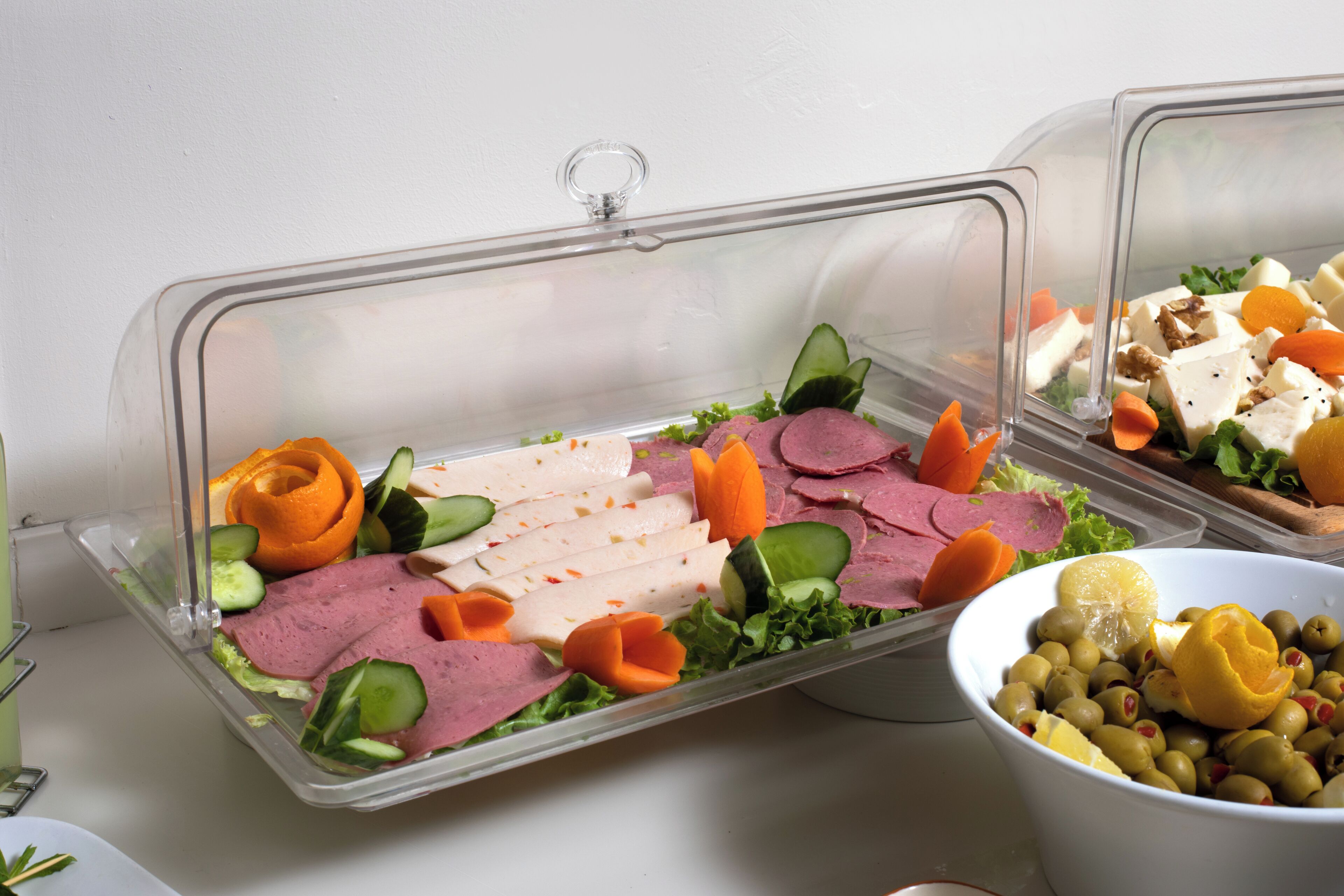 A buffet with various food items including meats, vegetables, and a bowl of olives.