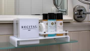 A bathroom shelf with a box labeled "RECITAL" and three bottles of varying colors.