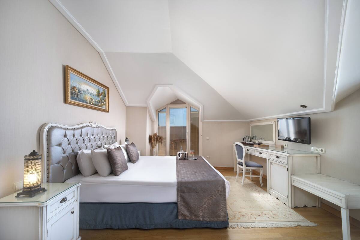 Une chambre avec un grand lit, un bureau, une télévision et une fenêtre donnant sur un beau paysage.