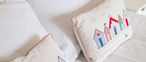 A bed with white bedding and two decorative pillows featuring a nautical theme.