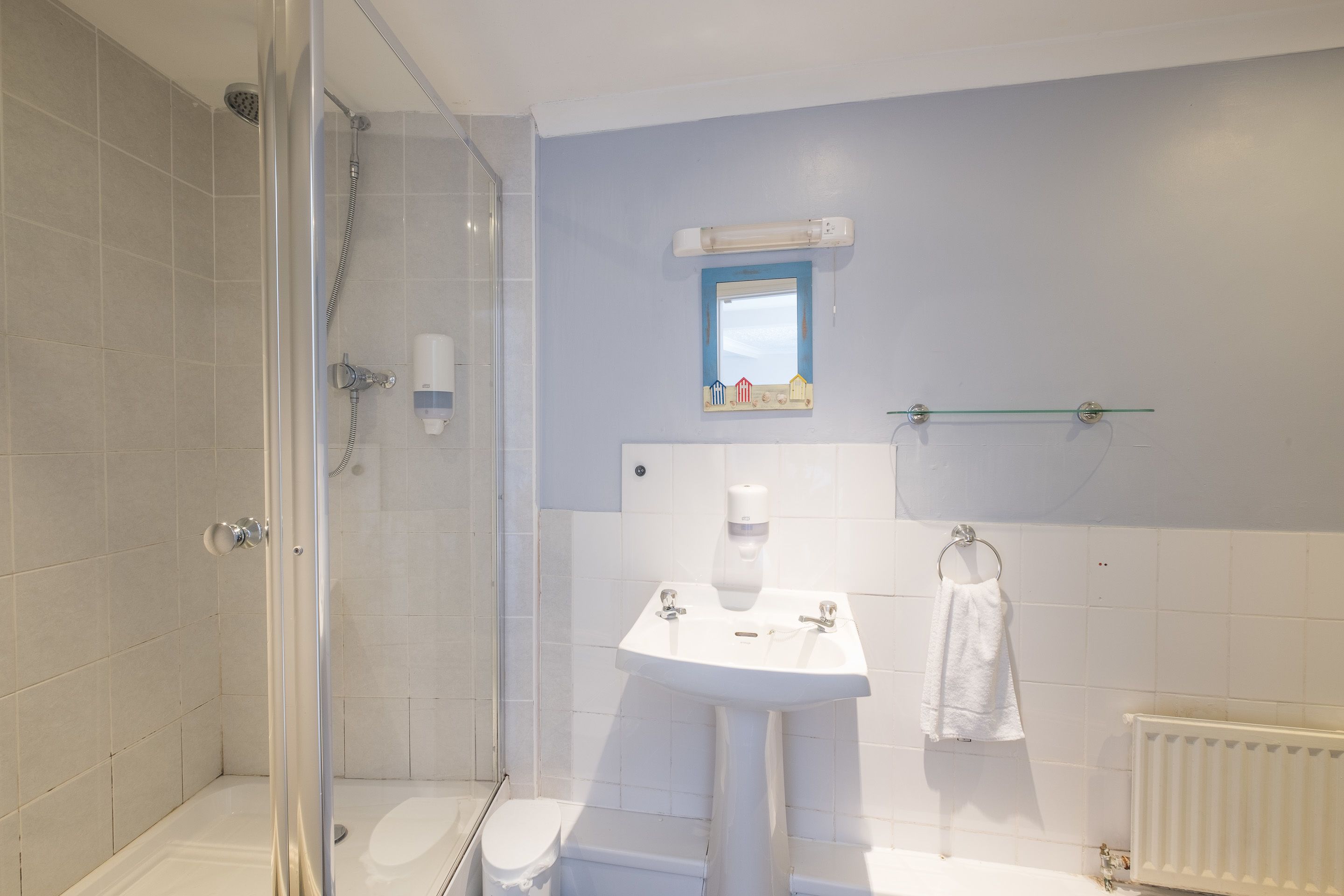 A bathroom with a glass-enclosed shower, a white sink, and a toilet.