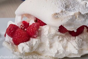 A dessert with whipped cream and raspberries.