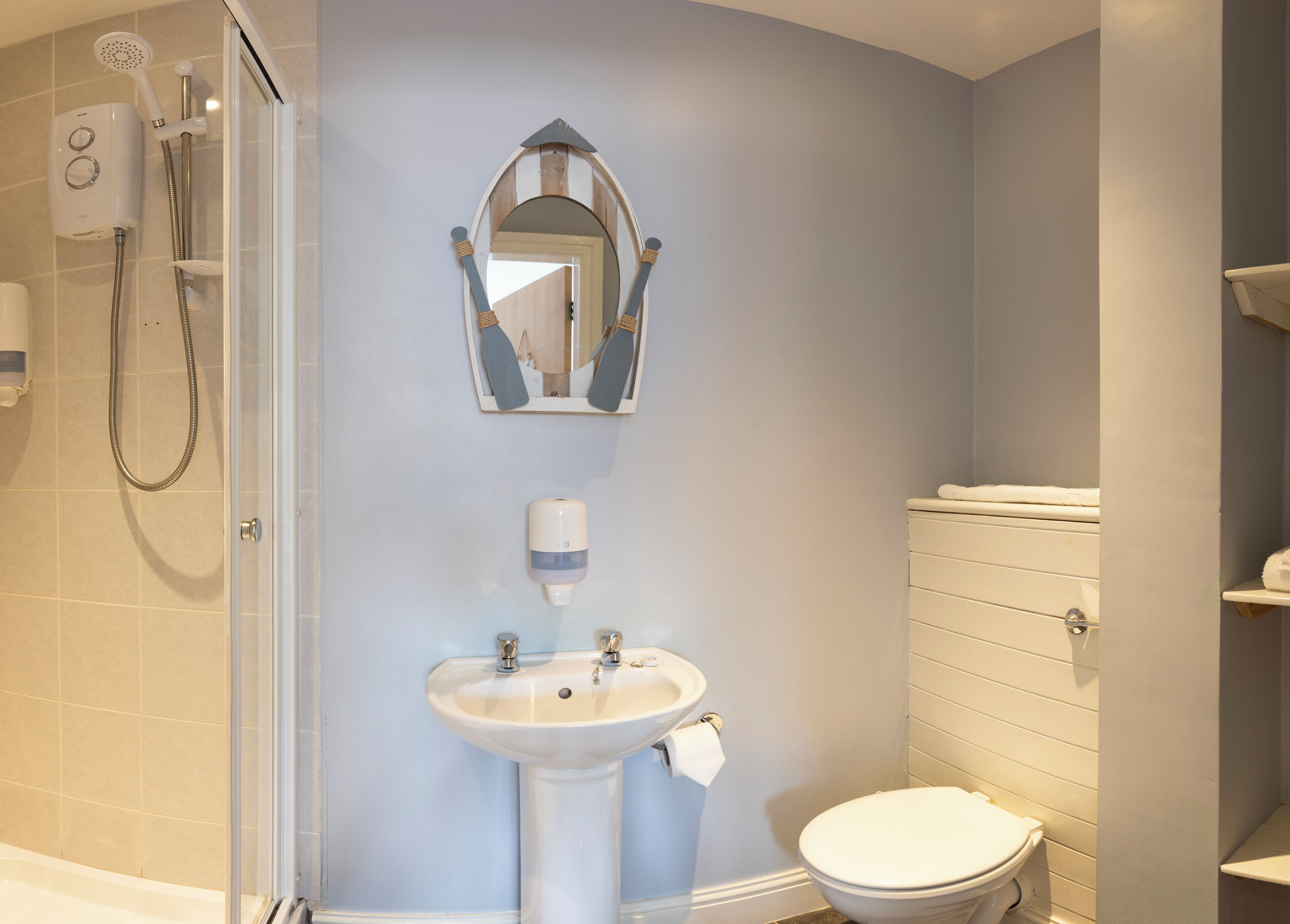 A bathroom with a shower, sink, toilet, and a mirror.