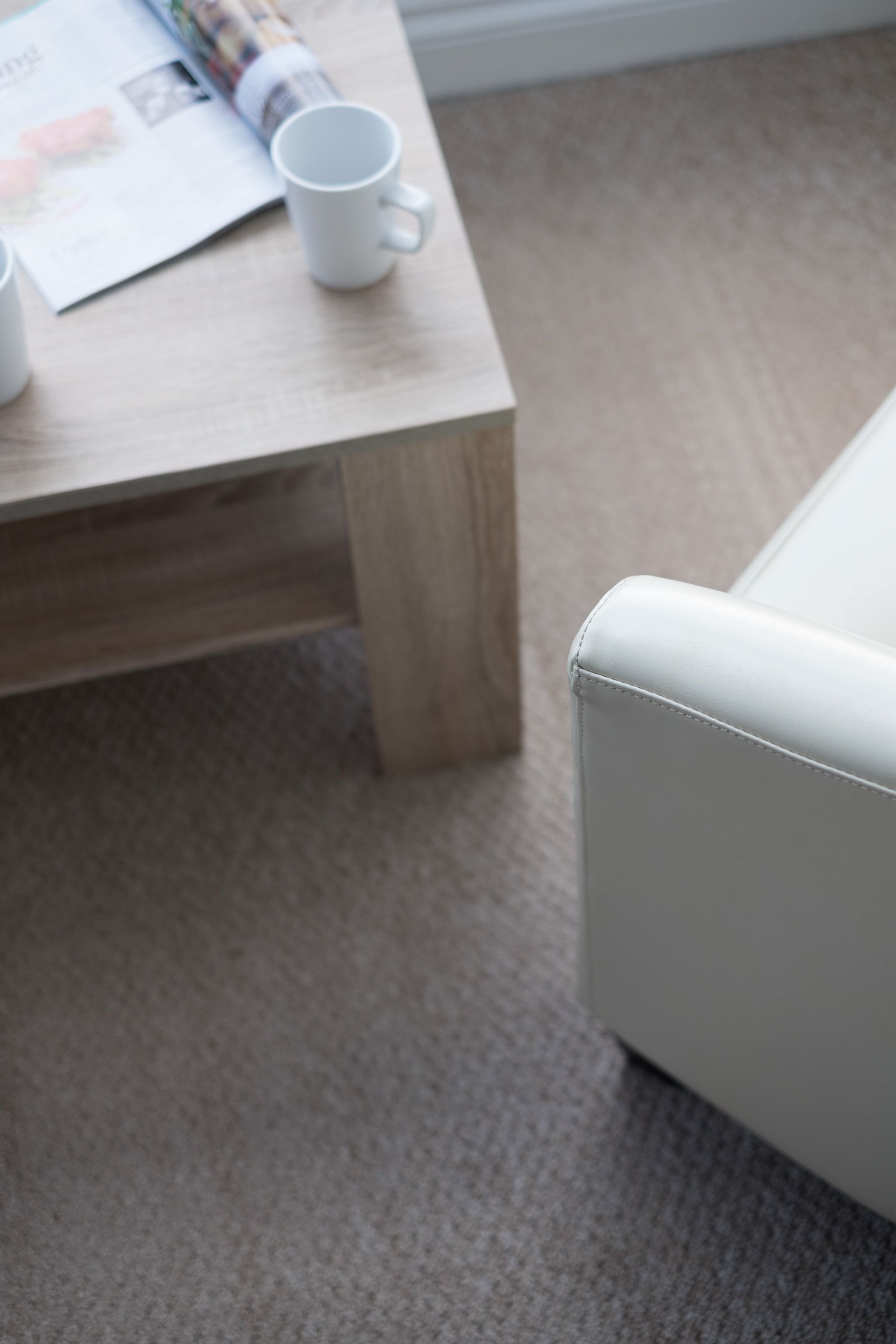 A wooden table with a white mug and a magazine.