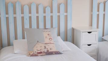 Cozy retreat with a bed, bedside table, and nautical-themed pillow.