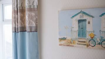 Quarto com pintura de uma casa de praia, uma bicicleta e um letreiro que diz 'BEACH'.