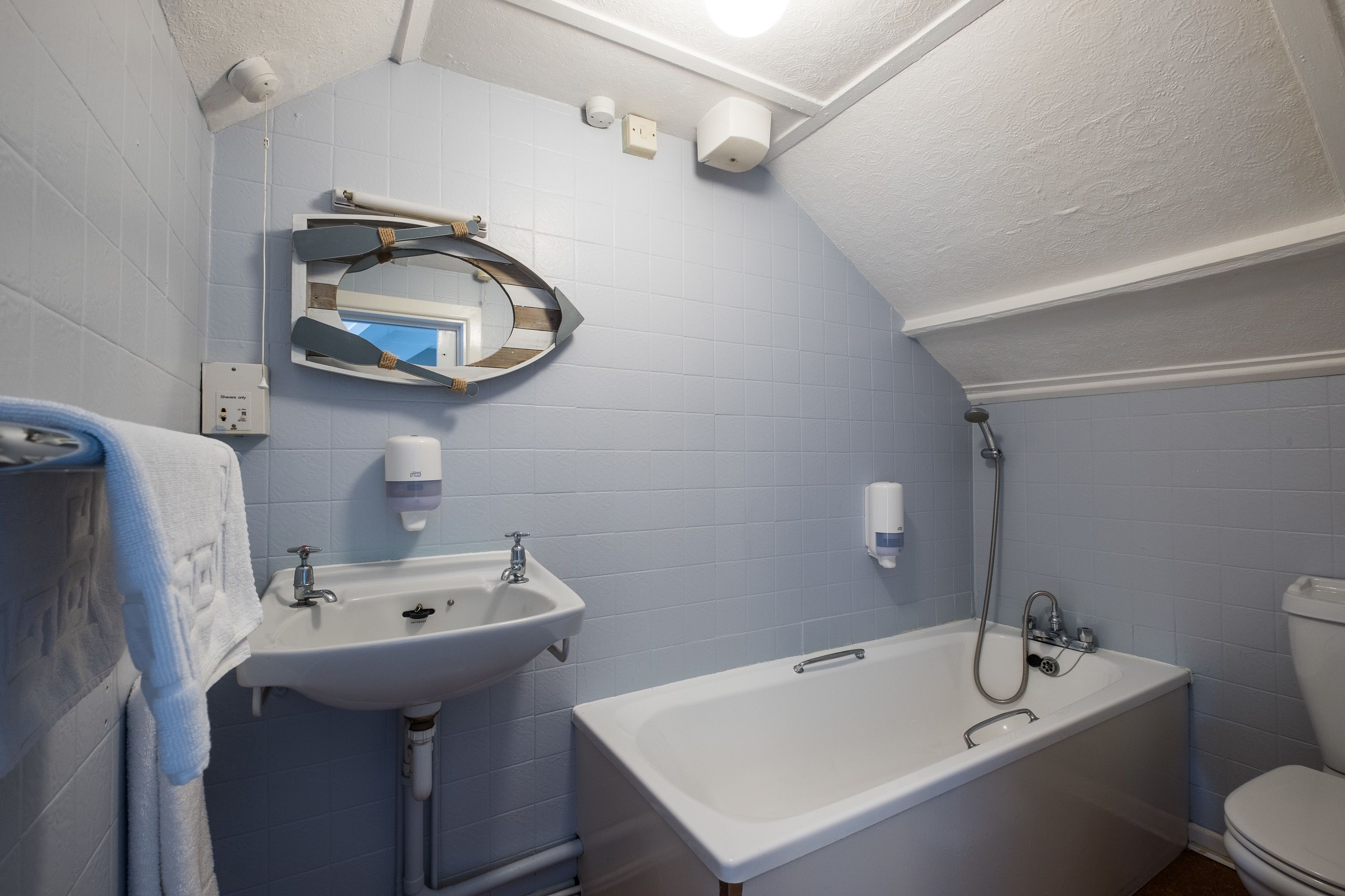 A bathroom with a white sink, a bathtub, and a toilet. There is a towel rack with a towel hanging on it.