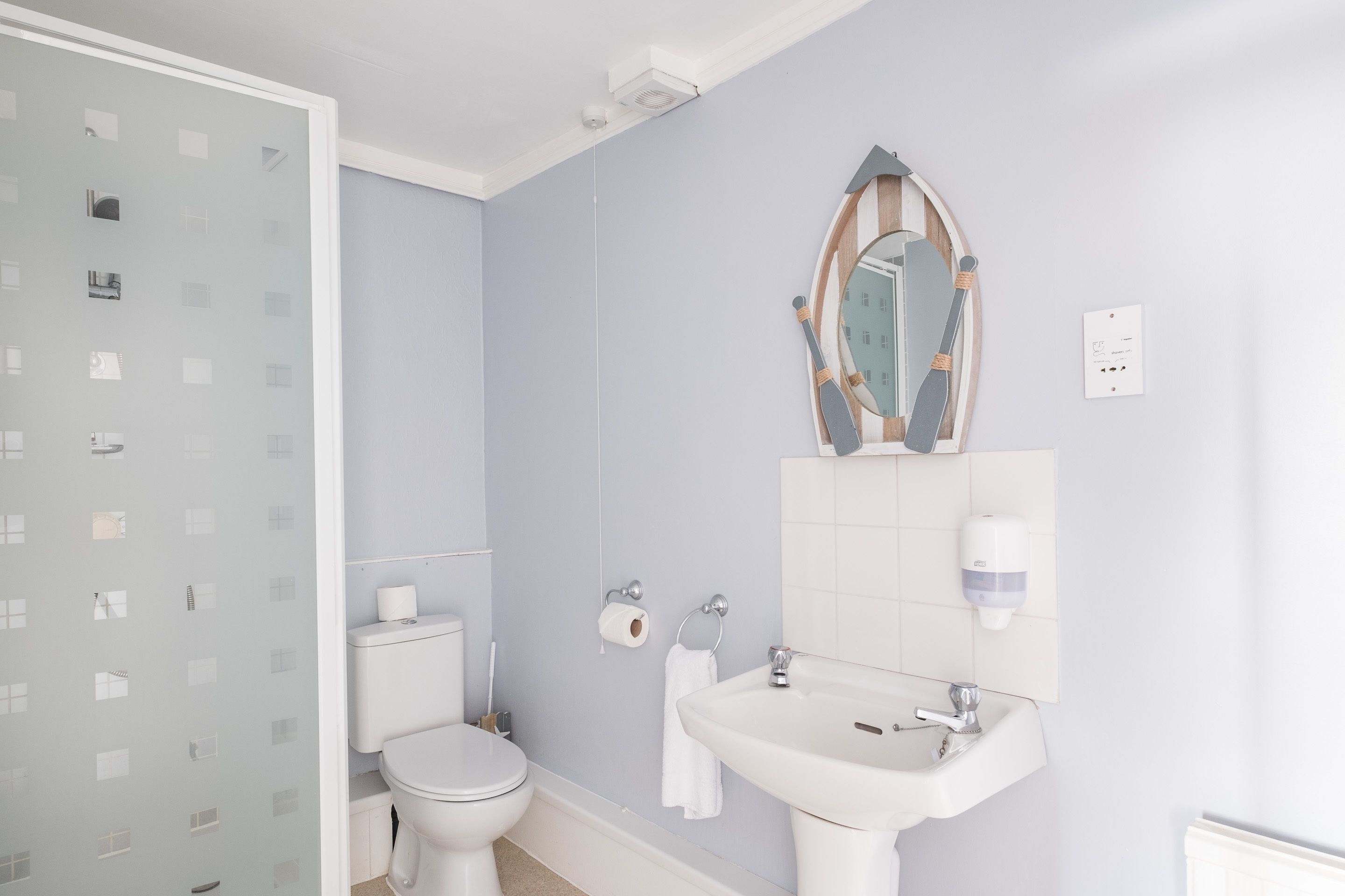 A bathroom with a toilet, sink, and mirror.