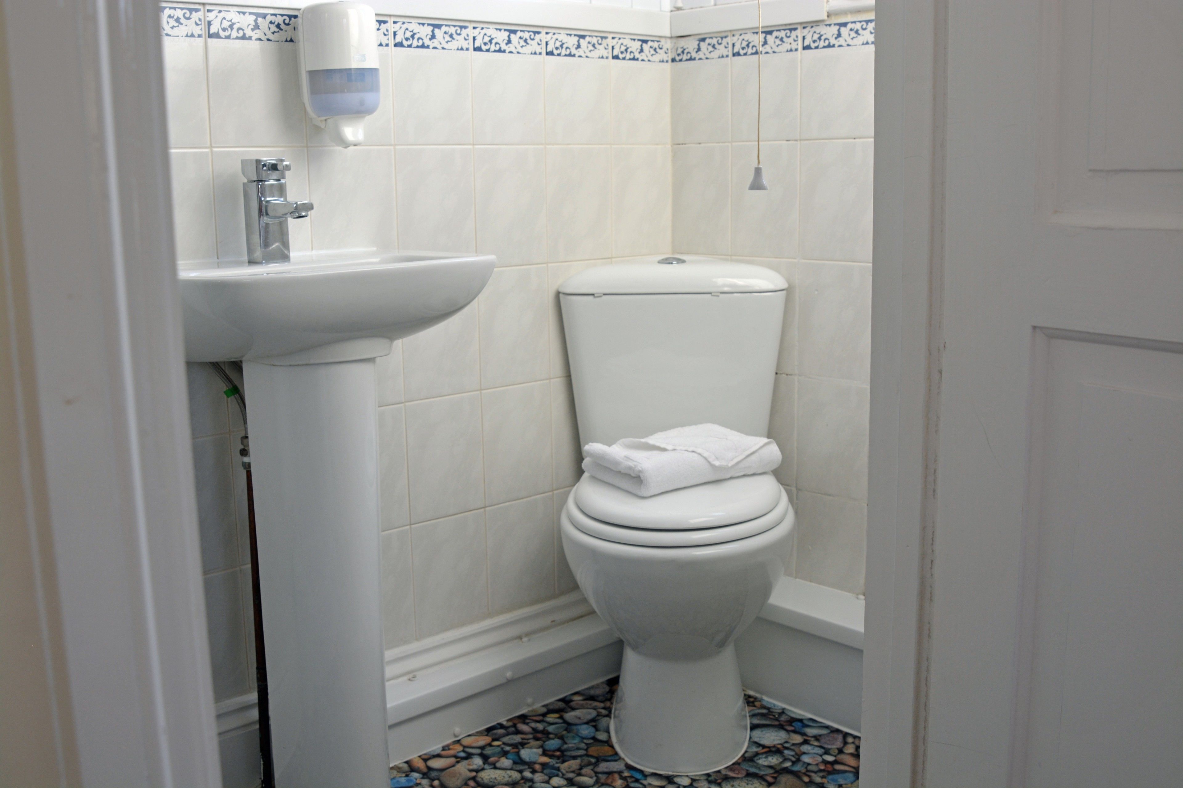A bathroom with a toilet, sink, and a tiled floor.