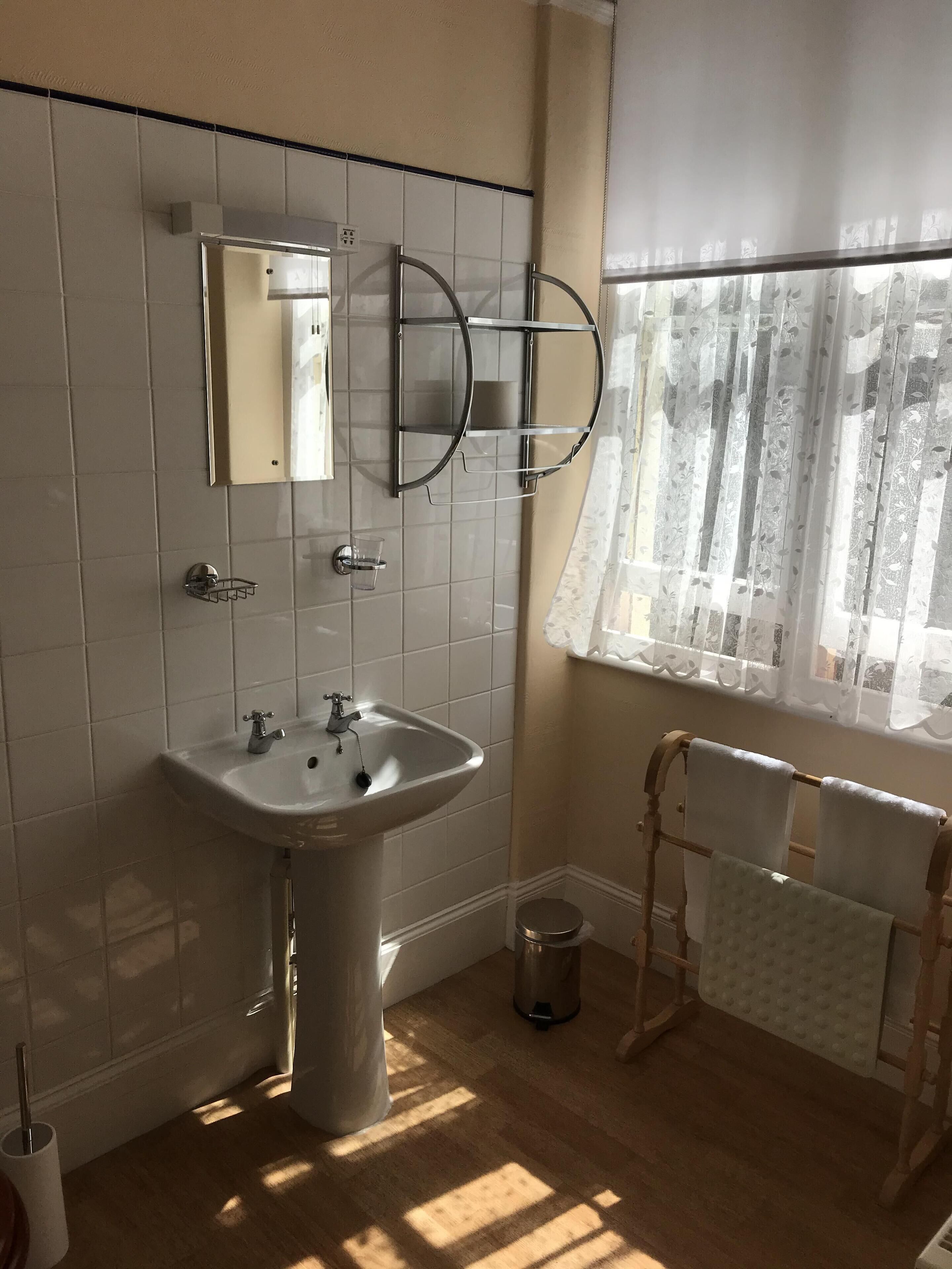 Un baño con lavamanos, espejo y toallero.