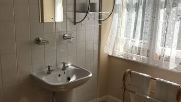 Une salle de bain avec un lavabo, un miroir et un porte-serviettes.
