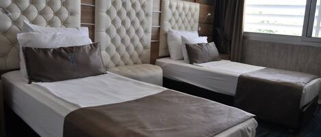 A hotel room with two beds, each with a headboard and pillows.