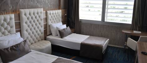 Quarto de hotel com duas camas, uma escrivaninha e uma janela com persianas.