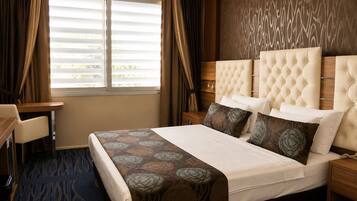 Ein Hotelzimmer mit einem großen Bett, einem Schreibtisch und einem Fenster mit Vorhängen.