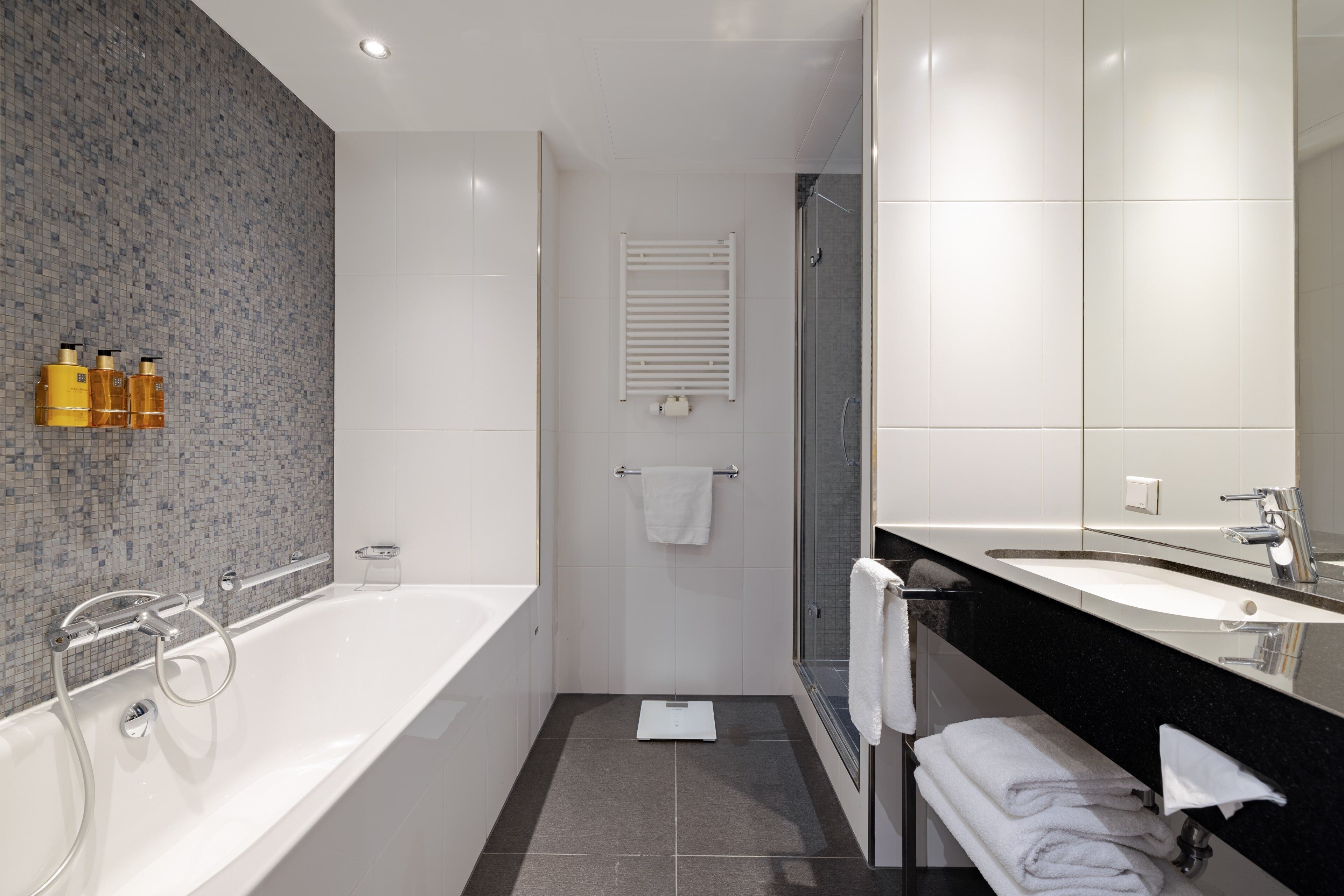 Une salle de bain moderne équipée d’une baignoire, d’une douche et d’un meuble-lavabo avec un miroir.