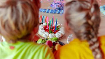 A birthday cake with candles, surrounded by party decorations.