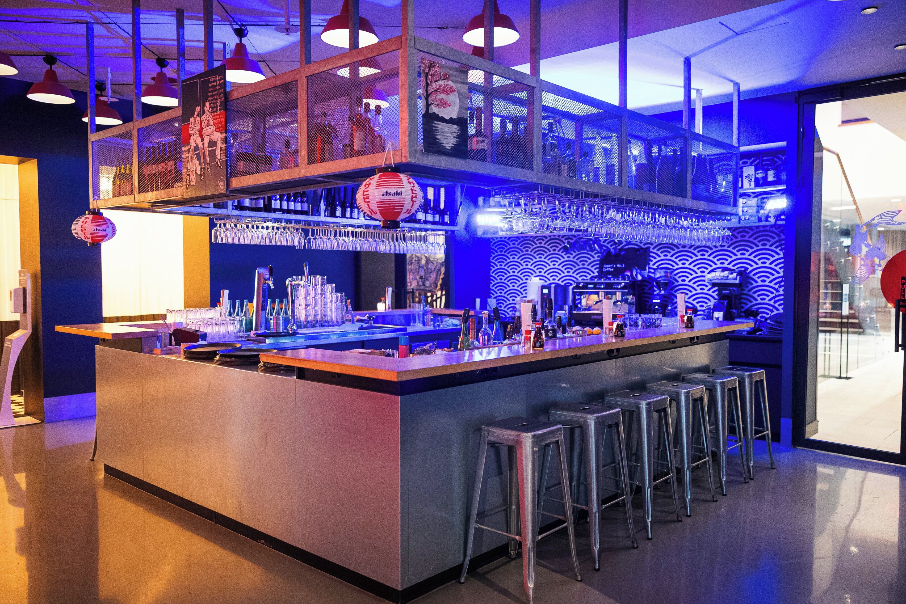 Un espace bar avec des tabourets, un comptoir et une variété de bouteilles et de verres.