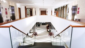 A modern hotel lobby with a central staircase, glass railings, and a polished floor. - Crowne Plaza Amsterdam South by IHG (Amsterdam)